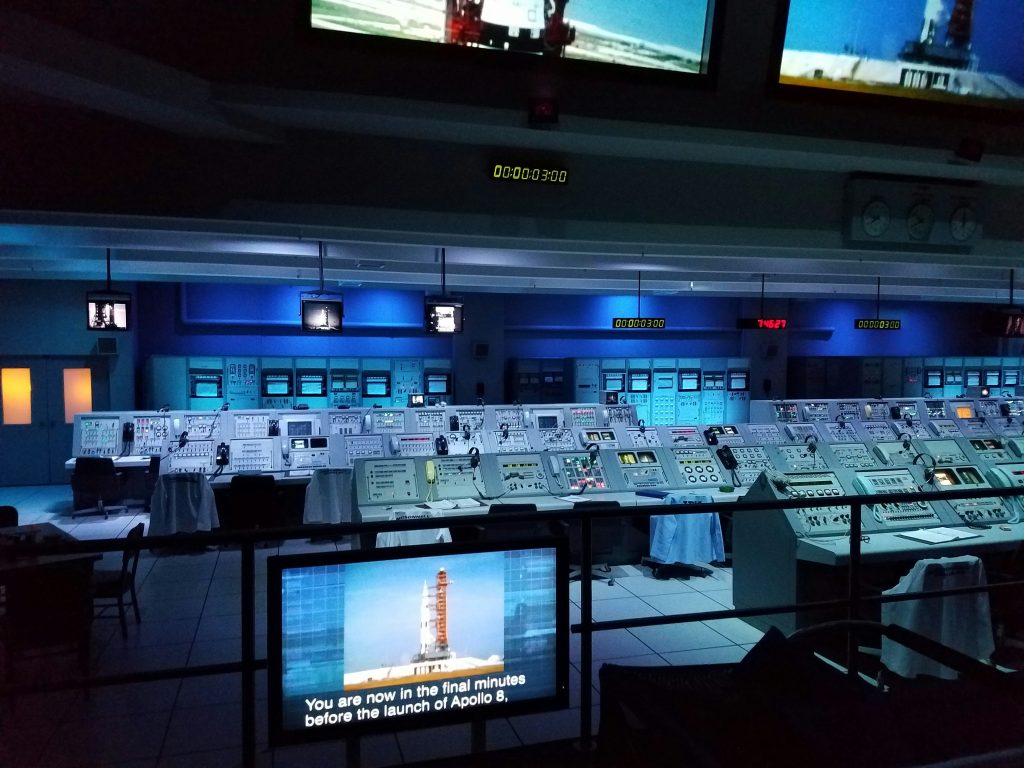 Mission control room with rows of glowing monitors and consoles