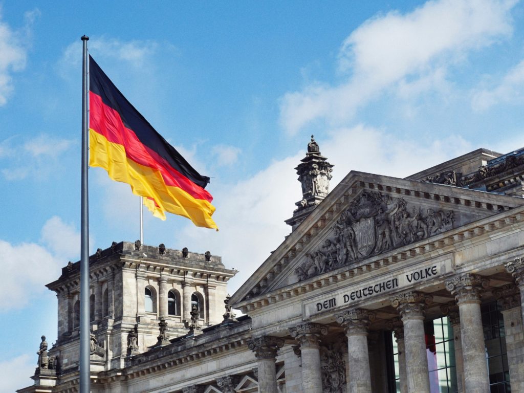 German flag flying above the Reichstag building in Berlin as Germany's federal government has signed a Joint Declaration of Intent with NVIDIA to advance cutting-edge AI models for industrial physical AI, with the agreement concluded at the Invest in Germany Summit.